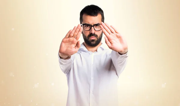 Knappe man met bril stopbord op okergeel achtergrond maken — Stockfoto