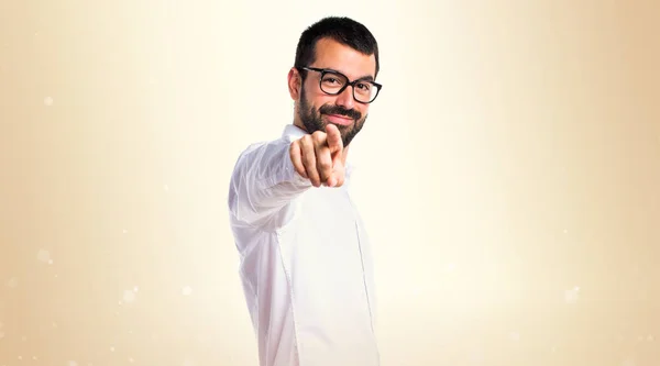 Handsome man with glasses pointing to the lateral on ocher backg — Stock Photo, Image