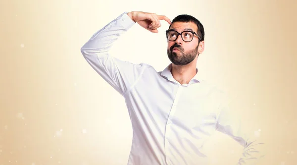 Hombre guapo con gafas que tiene dudas sobre el fondo ocre — Foto de Stock