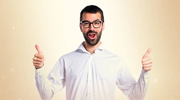 Hombre guapo con gafas con pulgar hacia arriba sobre fondo ocre — Foto de Stock