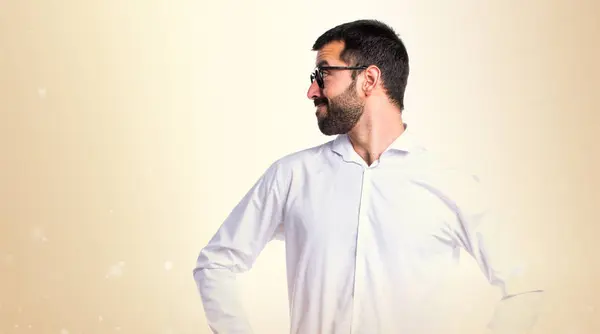 Hombre guapo con gafas mirando lateral sobre fondo ocre — Foto de Stock