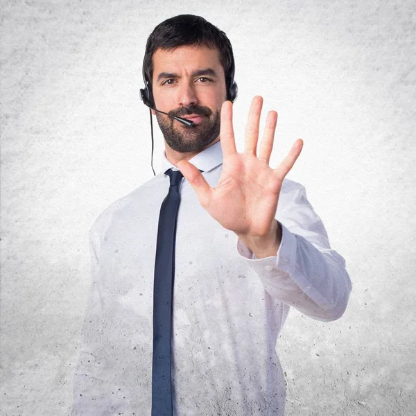 Jonge man met een headset tellen vijf op een gestructureerde achtergrond — Stockfoto