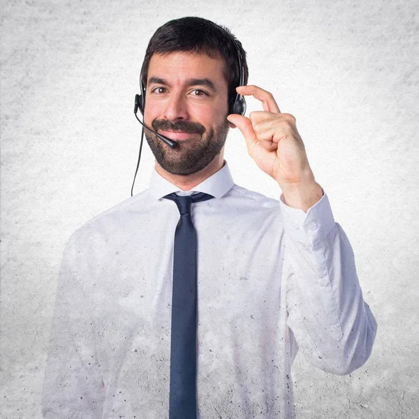 Junger Mann mit Kopfhörer, der winzige Zeichen auf strukturiertem Hintergrund macht — Stockfoto