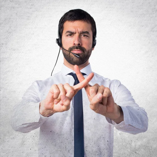 Jonge man met een headset doen geen gebaar op gestructureerde achtergrond — Stockfoto