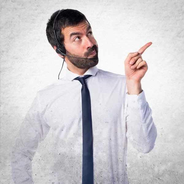 Joven con un auricular pensando en fondo texturizado — Foto de Stock