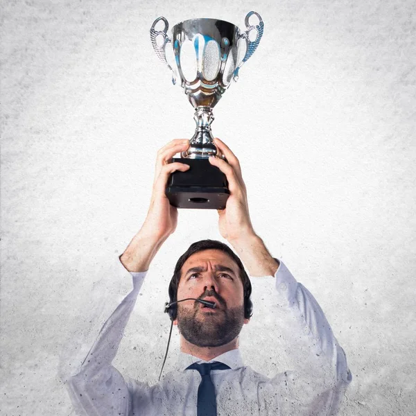 Handsome telemarketer man holding a trophy on textured backgroun — Stock Photo, Image