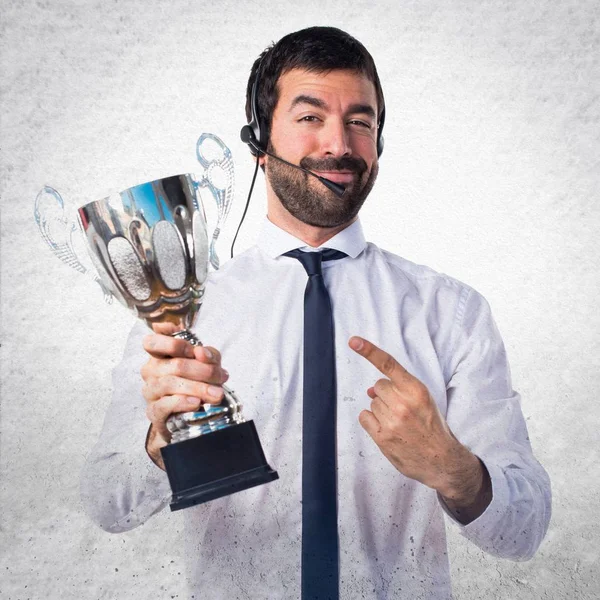 Hombre de telemarketer guapo sosteniendo un trofeo en fondo texturizado —  Fotos de Stock