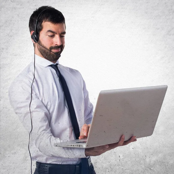 Yakışıklı telemarketer adam ile dokulu arka plan üstünde laptop — Stok fotoğraf