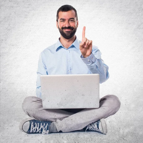 Homem com laptop contando um no fundo texturizado — Fotografia de Stock