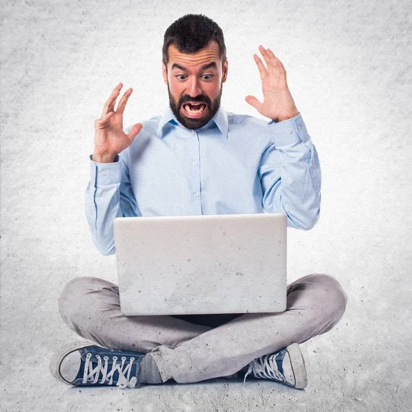 Frustrated man with laptop on textured background