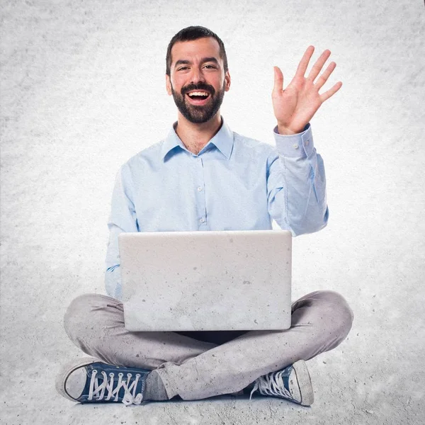 Homem com laptop saudação em fundo texturizado — Fotografia de Stock