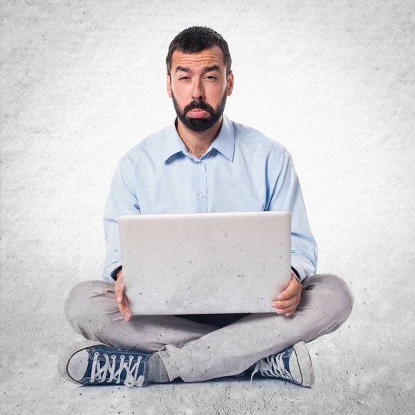 Triste homem com laptop em fundo texturizado — Fotografia de Stock