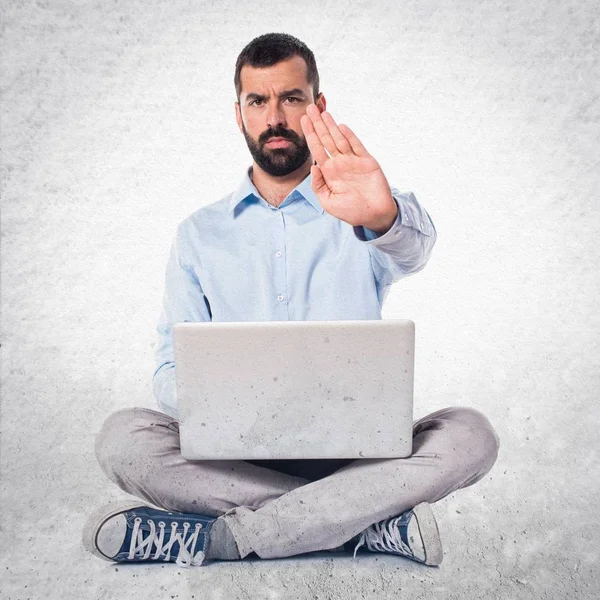 Homem com laptop fazendo sinal de parada no fundo texturizado — Fotografia de Stock