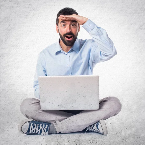 Homem com laptop mostrando algo sobre fundo texturizado — Fotografia de Stock