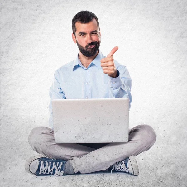 Homem com laptop com polegar para cima no fundo texturizado — Fotografia de Stock