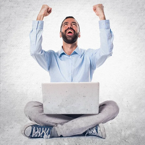 Lucky man with laptop on textured background