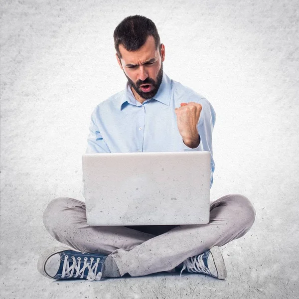 Lucky man with laptop on textured background