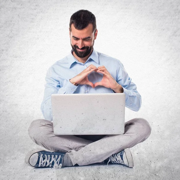 Ο άνθρωπος με το laptop καθιστώντας μια καρδιά με τα χέρια του σε ανάγλυφη έκφραση — Φωτογραφία Αρχείου