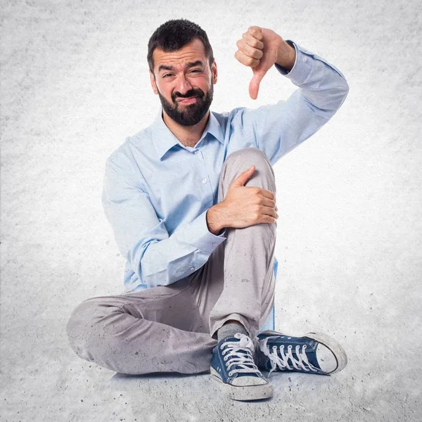 Handsome man doing bad signal on textured background