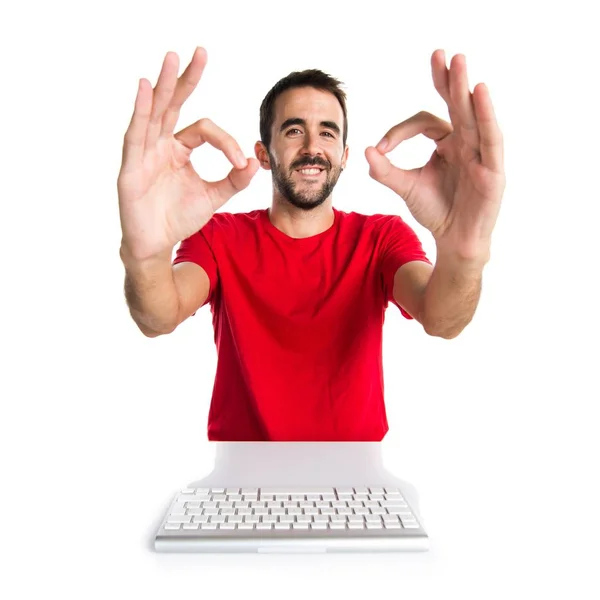 Комп'ютерний технік, який працює зі своєю клавіатурою, робить знак " Гаразд" — стокове фото