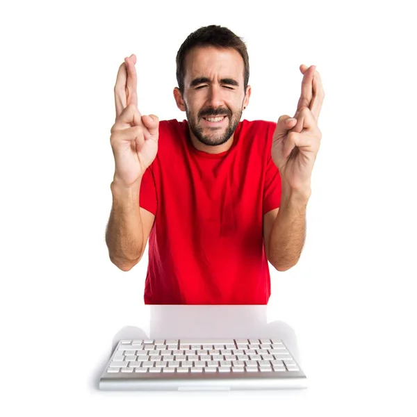 Комп'ютерний технік, що працює зі своєю клавіатурою, перетинаючи пальці — стокове фото