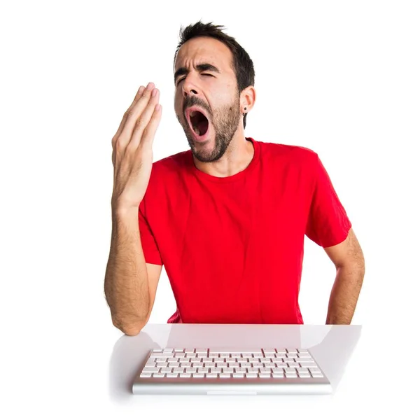 Computertechniker arbeitet gähnend mit seiner Tastatur — Stockfoto