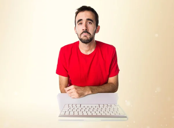 Sad computer technician working with his keyboard on ocher backg