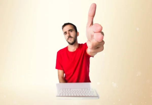 Комп'ютерний технік, який працює зі своєю клавіатурою, робить жест пістолета — стокове фото