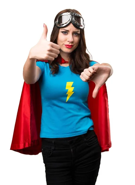 Menina super-herói bonito fazendo bom-mau sinal — Fotografia de Stock