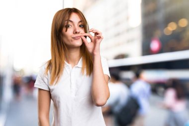 Güzel genç kız yapma sessizlik jest odaklanmamış arka plan üzerinde