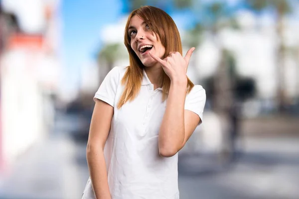 Beautiful young girl making phone gesture on unfocused background — Stock Photo, Image