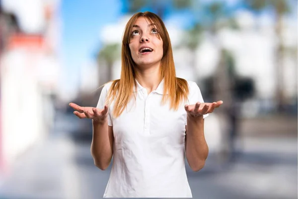 Hermosa chica joven suplicando sobre fondo desenfocado —  Fotos de Stock