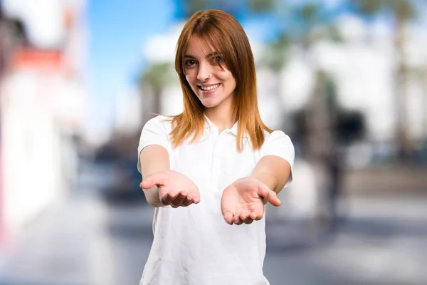 Schönes junges Mädchen hält etwas auf unkonzentriertem Hintergrund — Stockfoto