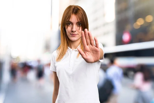 Hermosa chica joven haciendo señal de stop sobre fondo desenfocado —  Fotos de Stock