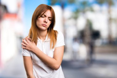 Omuz ağrısı odaklanmamış arka plan üzerinde güzel genç kızla