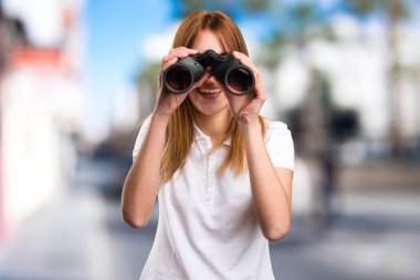 Odaklanmamış arka plan üzerinde dürbün ile mutlu güzel genç kız