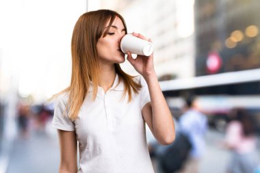 Bir fincan kahve odaklanmamış arka planda tutan güzel genç kız