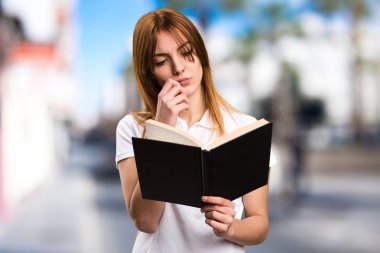 Güzel genç kız odaklanmamış arka plan üzerinde kitap okuma