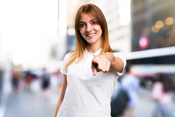 Schönes junges Mädchen, das auf unkonzentriertem Hintergrund nach vorne zeigt — Stockfoto