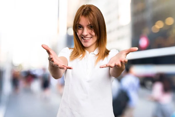 Schönes junges Mädchen, das etwas auf unkonzentriertem Hintergrund präsentiert — Stockfoto