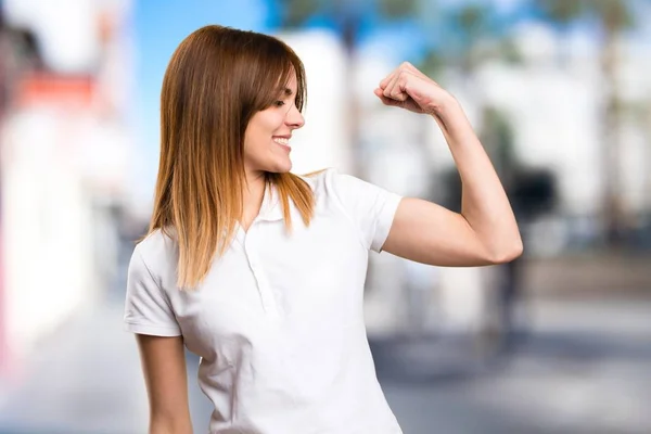 Mooi jong meisje sterke gebaar maken op ongericht achtergrond — Stockfoto