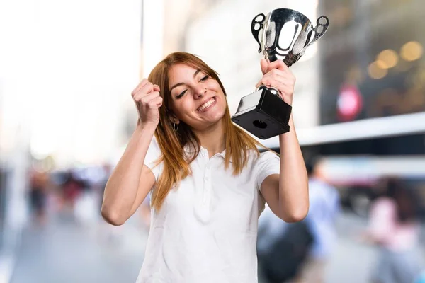 Feliz menina bonita segurando um troféu em fundo desfocado — Fotografia de Stock