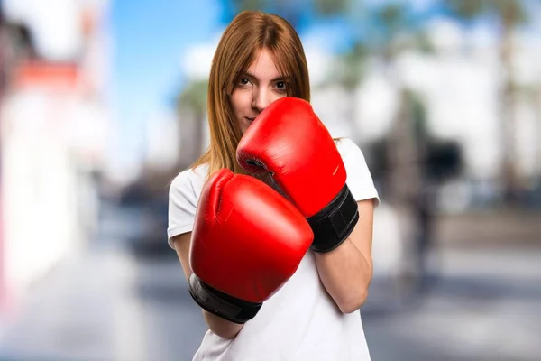 Schönes junges Mädchen mit Boxhandschuhen auf unkonzentriertem Hintergrund — Stockfoto