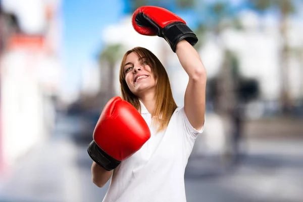 Glücklich schönes junges Mädchen mit Boxhandschuhen auf unkonzentriertem Hintergrund — Stockfoto