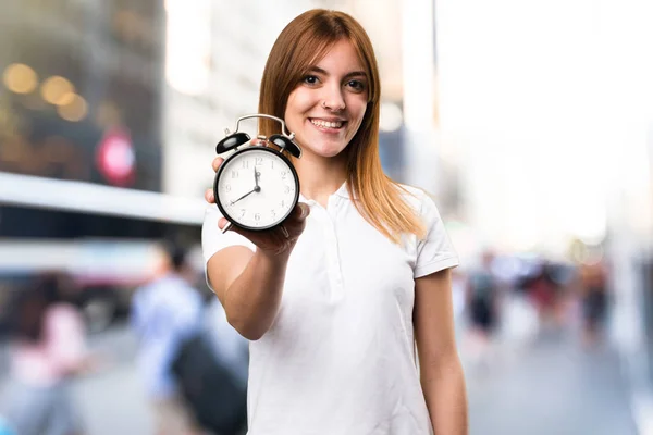 Happy Beautiful young girl holding vintage clock on unfocused ba — Stock Photo, Image