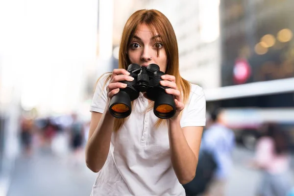 Förvånad över vacker ung flicka med kikare på ofokuserat bakgrund — Stockfoto