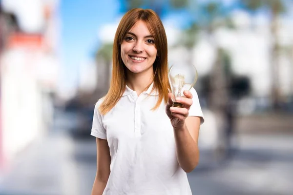 Glücklich schönes junges Mädchen hält eine Glühbirne auf unkonzentriertem Hintergrund — Stockfoto