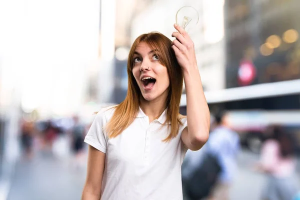 Sorpreso Bella ragazza che tiene una lampadina su sfondo sfocato — Foto Stock