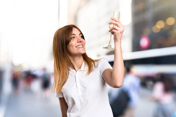 Счастливая молодая девушка с шампанским на расфокусированном фоне — стоковое фото