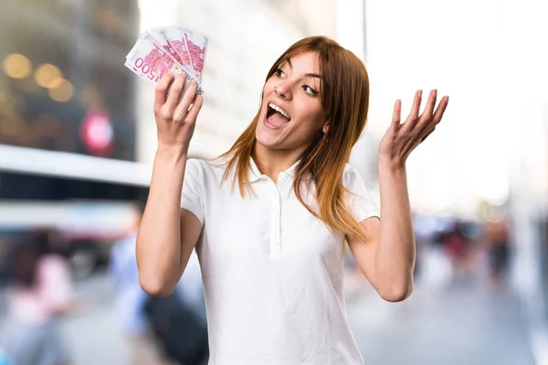 Surpreendido bela menina tomando um monte de dinheiro em unfocuse — Fotografia de Stock